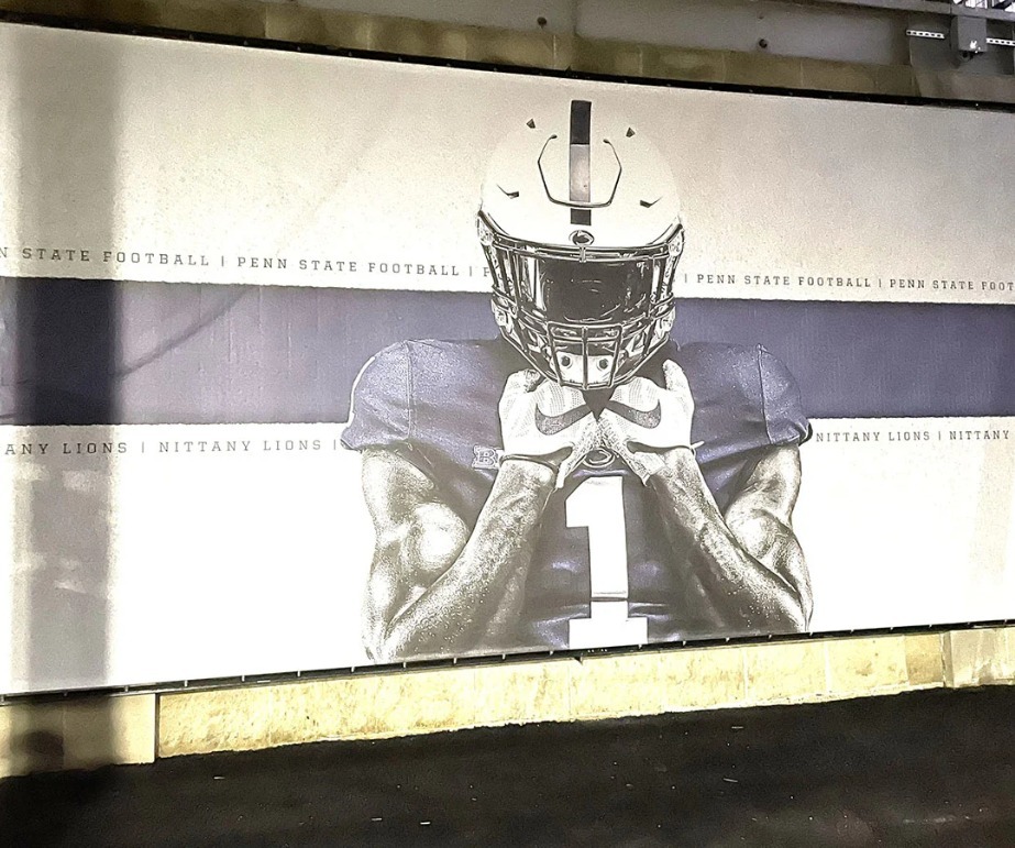 A close-up of a large black-and-white graphic of a football player displayed on a wall with Penn State text.
