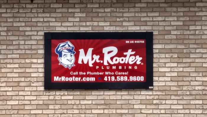 A Lind SignSpring Product – BannerFrameCLASSIC With Covers for Mr. Rooter Plumbing on the exterior brick wall-Horizontal Side Wall Banner