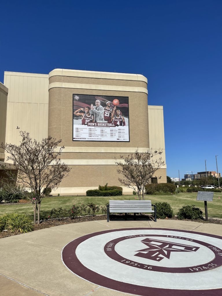 Lind-SignSpring-Lewis-Signs-12th-Man-TexasAM-BannerFrame-CLASSIC-with-covers-on-brick-mens-basketball-768x1024 The 12th Man - Texas A&M Know Who To Call In