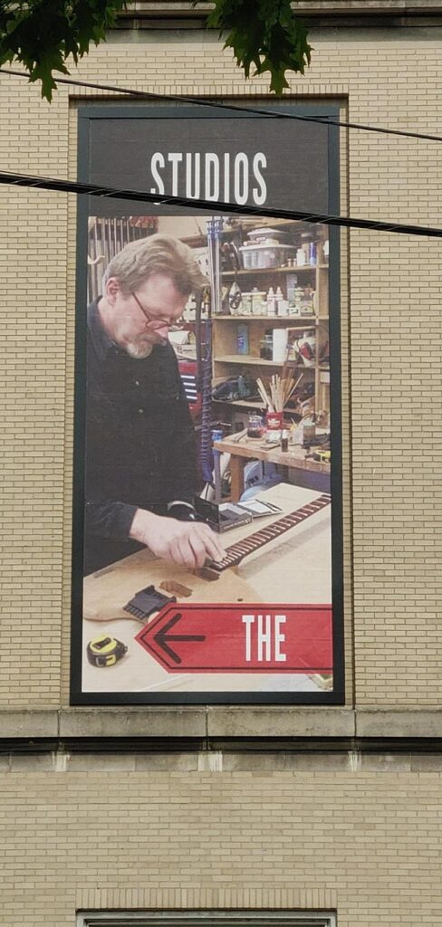 Picture-of-a-man-working-on-a-guitar-with-the-word-studios-488x1024 Lind BannerFrame CLASSIC: Custom Banner Signs for Your Aging Brick Wall