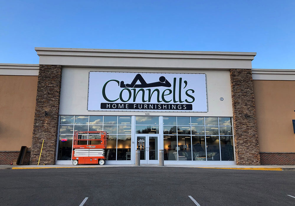 A Lind SignSpring Product – BannerFrameCLASSIC With No Covers for the Connell’s Home Furnishings on an exterior store entrance concrete wall